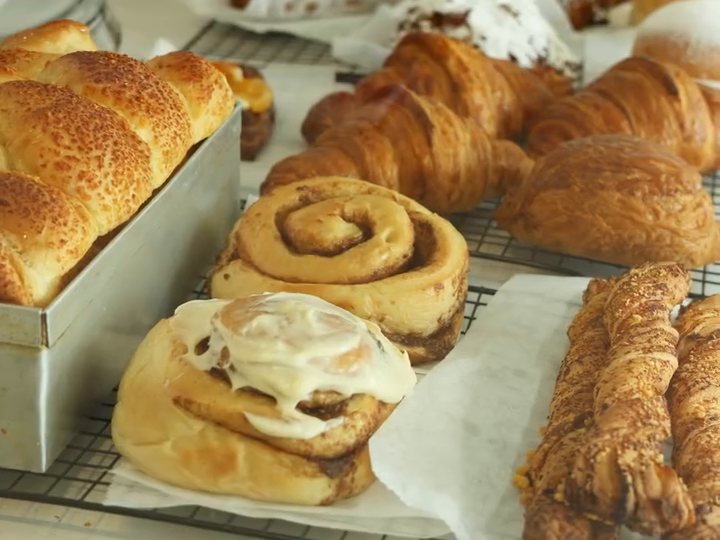 Vitrina de La erre con trenza de queso, rollos de canela glaseados, croissants y bastones de canela